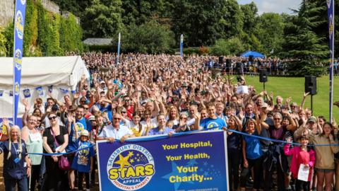 A large crowd of people all facing the camera and waving