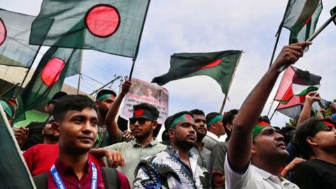 Demonstrators wave Bangladesh's national flag during Martyr March, a rally organised by Students Against Discrimination to mark one month to the ousting of the country's former Prime Minister Sheikh Hasina, in Dhaka on September 5, 2024. Bangladesh's ousted premier Sheikh Hasina should "keep quiet" while exiled in India until she is brought home for trial, interim leader Muhammad Yunus told Indian media on September 5. Hasina, 76, fled to India by helicopter one month ago as protesters marched on her palace in a dramatic end to her iron-fisted rule of 15 years. (Photo by Munir UZ ZAMAN / AFP) (Photo by MUNIR UZ ZAMAN/Demonstrators wave Bangladesh's national flag during Martyr March, a rally organised by Students Against Discrimination to mark one month to the ousting of the country's former Prime Minister Sheikh Hasina, in Dhaka on September 5, 2024. Bangladesh's ousted premier Sheikh Hasina should "keep quiet" while exiled in India until she is brought home for trial, interim leader Muhammad Yunus told Indian media on September 5. Hasina, 76, fled to India by helicopter one month ago as protesters marched on her palace in a dramatic end to her iron-fisted rule of 15 years. (Photo by Munir UZ ZAMAN / AFP) (Photo by MUNIR UZ ZAMAN/AFP via Getty Images))