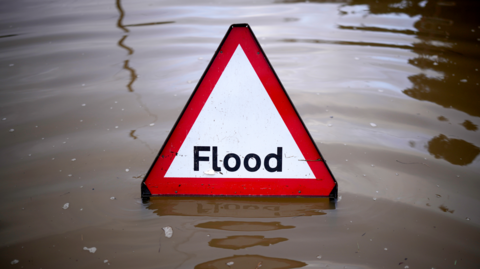 A triangular flood sign in a pool of water