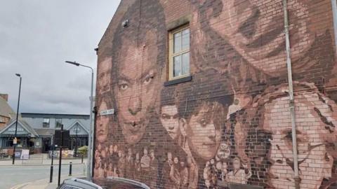 The side of a brick building in Hull, which has been painted with more than 20 musical figures from Hull, including Roland Gift and Mick Ronson.