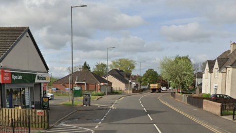 A Post Office and Morrisons shop on the left side of a road with houses opposite