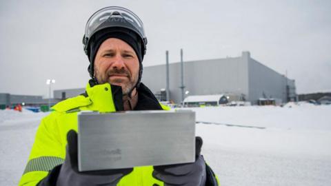 A Northvolt worker holds up a battery outside the Northvolt plant in Skellefteå, Sweden