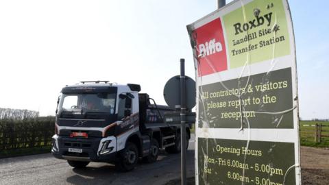 A small tipper lorry passing a roadside sign which reads: Biffa Roxby landfill site and transfer station.