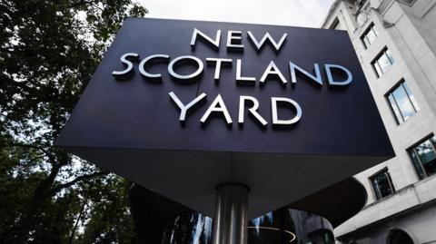 A revolving sign outside Met police headquarters that says New Scotland Yard