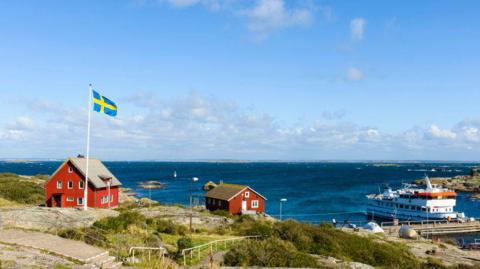 A Swedish island with the flag of Sweden flying high on a pole.