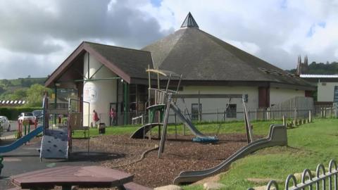 Totnes leisure centre. A circular building which looks like a church. A children's play area is in the foreground. 