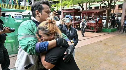 Family members of a school shooting victim mourn as bodies of the deceased are placed into ambulances at the school in Bang Kruai district, Nonthaburi province, north of the Thai capital Bangkok