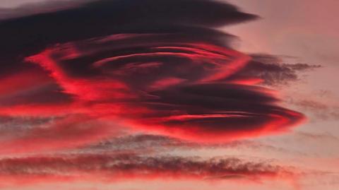 Layers of dark cloud illuminated red around the edges 