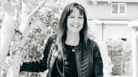 A black and white image of a woman in a black leather jacket, with long dark hair
