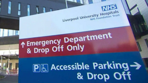 A close-up of a hospital sign which reads 'NHS Liverpool University Hospitals NHS Foundation Trust'. It also directs people to the A and E department, as well as an accessible parking drop-off area.