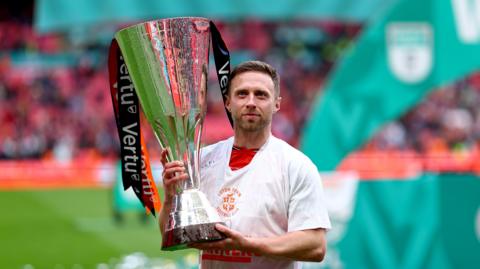 Luton Town midfielder Jordan Clark holding the Vertu Trophy after his side's victory at Wembley Stadium.