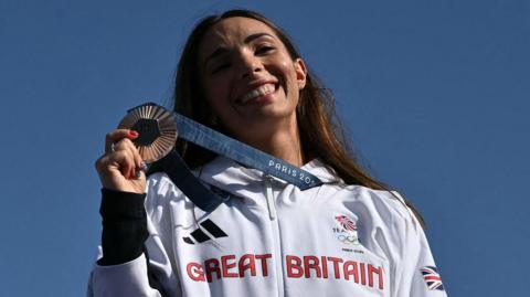 Team GB diver Yasmin Harper smiles as she holds up her bronze medal