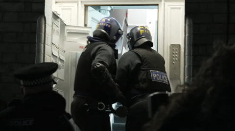 Two GMP officers batter down the door of one address during the raids. They've heavily clothed and both hold an instrument designed to open the front door.