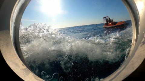 Water hits the window of a submersible in the Atlantic ocean, seen from inside the window