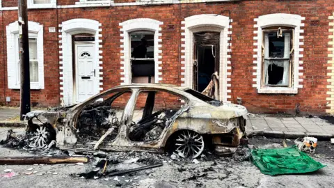 Police vehicle outside homes on fire 