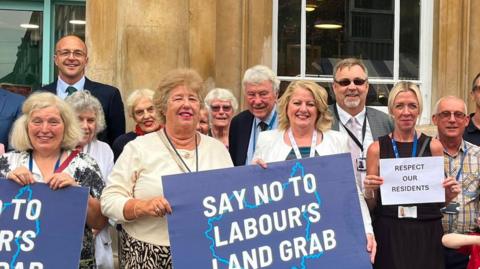 People holding placards saying "Say not to Labour's Land Grab."
