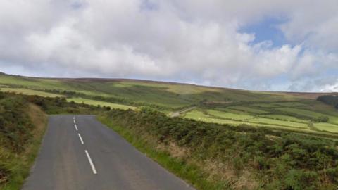 A long winding counrtyside road amid lush green fields.