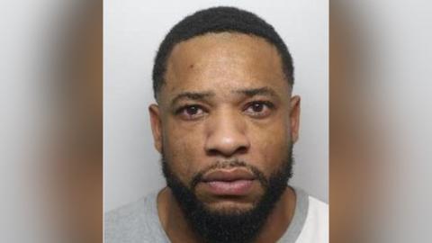 A mugshot of Louis Walters, a black man with short, curly black hair and a beard