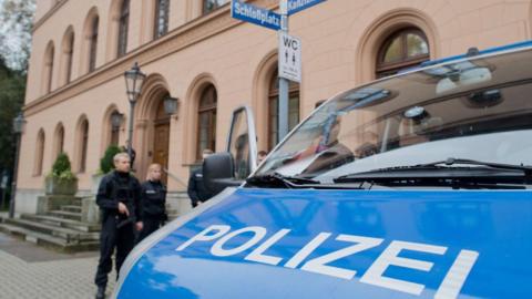 A stock image taken outside of the court in Celle. Some police officers can be seen in the mid-distance, with the bonnet of a police van visible in the near ground, with the word 'Polizei' written on the bonnet