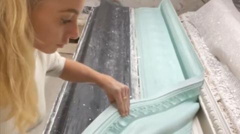 Mary-Havana Little works with a plaster mould. She has long blonde hair. hair