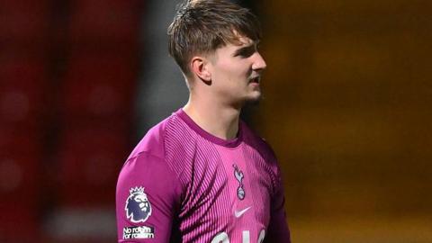 Luca Gunter looking right of image in a pink and purple Spurs goalkeeper shirt