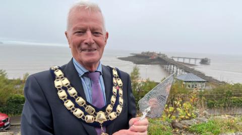 John Crockford-Hawley holding the trowel which his cousin used to lay the pier's foundation stone