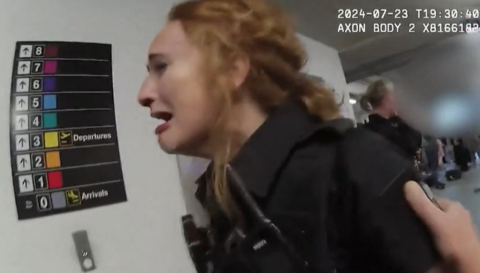 Police officer cries in pain. An airport sign behind her