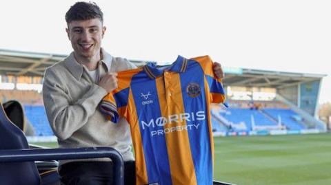 Callum Stewart holds up a Shrewsbury shirt