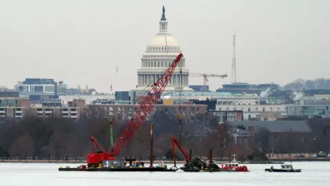 A salvage barge with a crane retrieves wreckage near the crash site of American Eagle Flight 5342 at Ronald Reagan Washington National Airport in Arlington, Virginia,