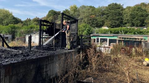 Firefighter hosing down burned building