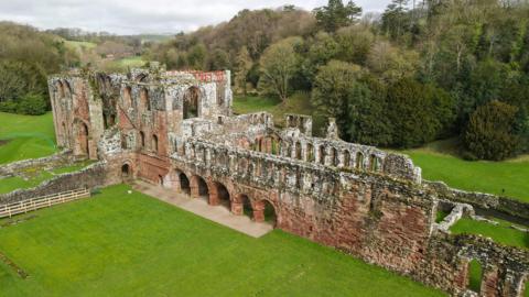 An aerial shot of the ruin of Furness Abbey. Large portions of the abbey are still intact and it is surrounded by woodland.