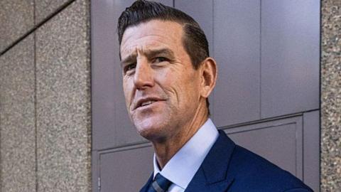 A brunette man wearing a navy suit pictured outside court