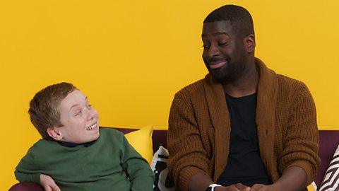 Two people smiling at each other on a sofa