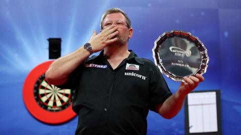 James Wade of England poses with his runners-up plate after defeat to Luke Littler in the World Matchplay final 