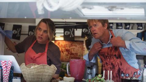 Characters in Beyond Paradise working in a food van, looking out the window with a shocked look on their face.