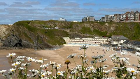 Blue sky with patchy cloud over a sandy bay with beach huts