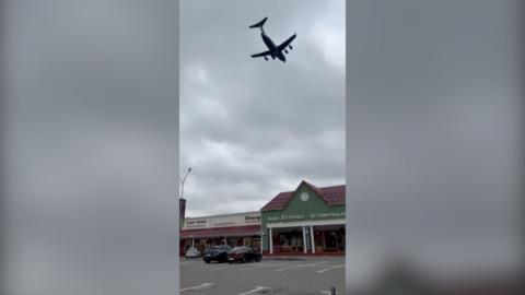 Screengrab of a video showing a plane flying at low altitude over a building in Moscow
