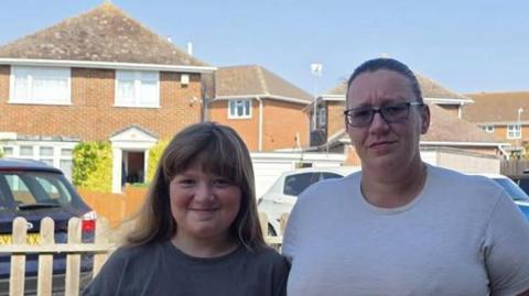 Lee-Anne Moore stands beside her daughter outside a home on Sheppey after raising concerns about a secondary school place offered in Faversham.