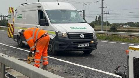 A workman working on a crash barrier on the A6, Bedfordshire