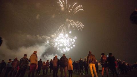 People gathered in a field to watch a firework display.