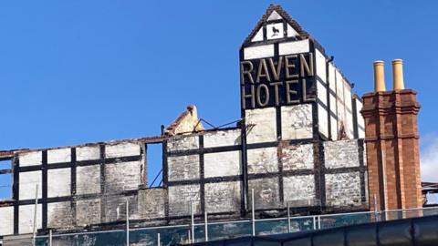 A shot of the front of the old Raven Hotel - the words 'Raven Hotel' can be seen on the old black and white period frontage.