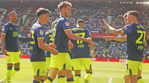 Liam Lindsay (middle) is about to get a high-five from Alfie Devine (right) with other team-mates around them