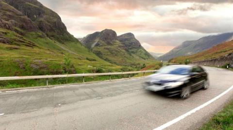 A car, blurred with movement, on the A82 in Glen Coe