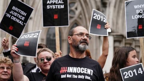 Andrew Malkinson wearing a t-shirt saying 'innocent' and surrounded by demonstrators holding placards