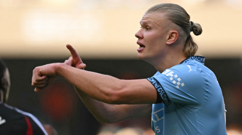 Erling Haaland gestures to an imaginary watch on his wrist