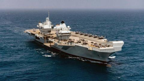 An aerial image of the HMS Prince of Wales aircraft carrier taken from above. The ship is on an open ocean.