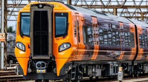 A West Midlands Railway train with carriages painted purple on the outside and orange doors.