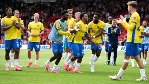 Portsmouth players, wearing their yellow and blue away kit, celebrate after the 3-1 win at Lincoln