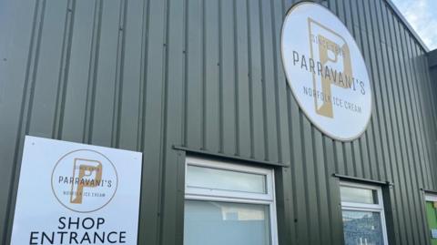 A large dark green-coloured warehouse-type unit with a large sign on it which reads Parravani's Norfolk Ice Cream.