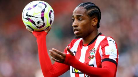 Kyle Walker-Peters playing for Southampton and holding a football in his right hand